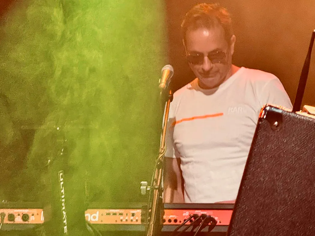 Der Keyboarder von Johnny Stone mit Sonnenbrille spielt hinter seinem Keyboard, davor grüner Bühnennebel.